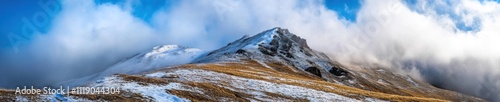 Snow capped mountain peaks shrouded in mist and clouds