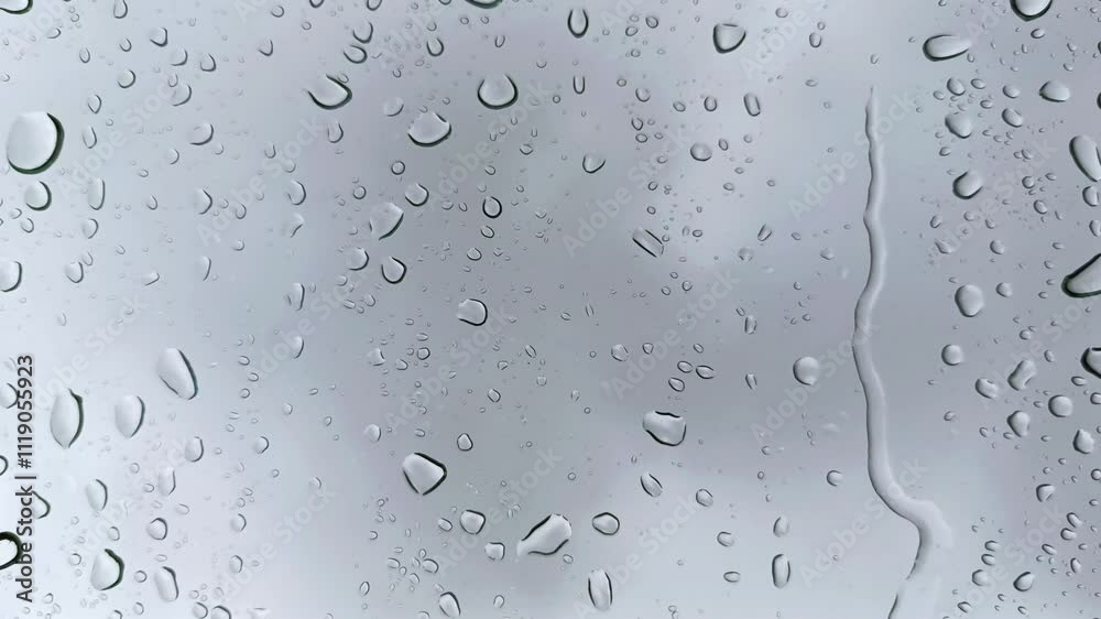 Raindrops flowing down the window glass with a dark cloud background