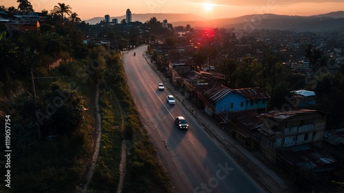 Sunset over a winding road with cars and urban landscape.