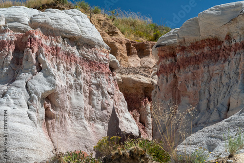 Colorful rock formations and layered sediment reveal the geological history of a natural landscape under a clear blue sky in the afternoon sunlight photo