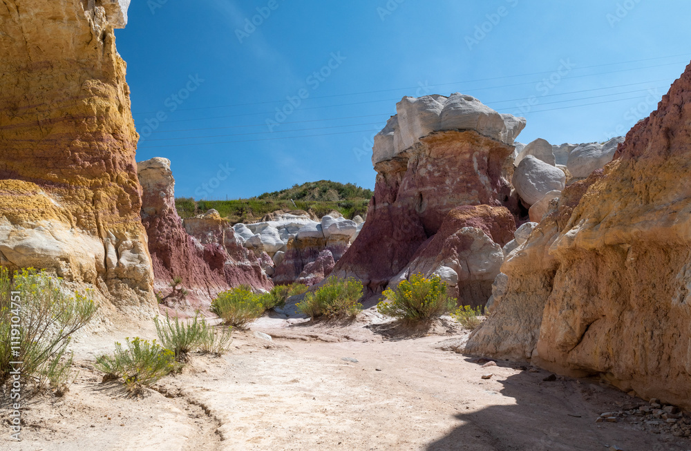 Fototapeta premium Breathtaking view of colorful rock formations under a clear blue sky in a serene canyon at midday, showcasing natural beauty and geological diversity in a remote area