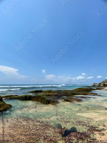 Bali, Indonesia - October 26, 2024: showing a beautiful beach with towering cliffs, decorated by lush green vegetation on Suluban Beach. photo