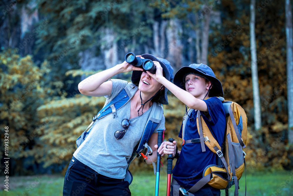 Naklejka premium Hikers or explorers on journey carrying backpack, trekking poles and holding binoculars looks into the distance observing and possibly guide trekking and trail exploration holiday ecotourism concept.