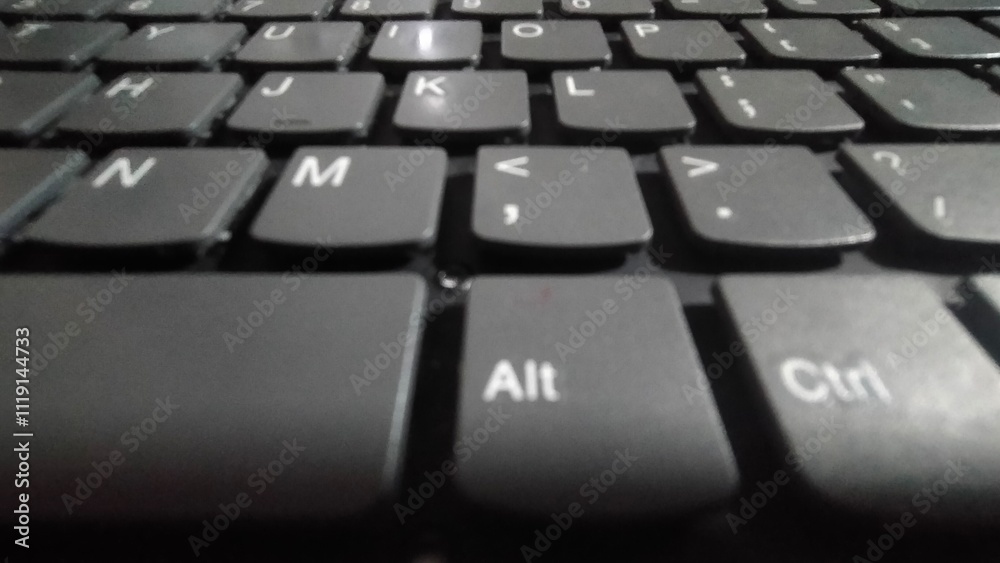 A minimalist, black laptop keyboard with clean, white keys, isolated on a wooden background. A minimalist, black laptop keyboard with clean, white keys, isolated on a wooden background.