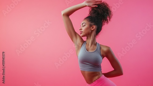 Sporty young woman in sportswear does stretching on a pink background