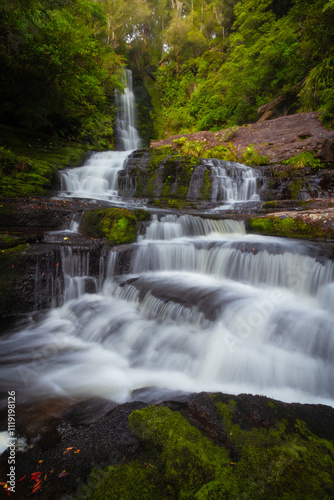 The McLean Falls is located on the Tautuku River in Catlins Conservation Park and have a two-tiered falls that cascades down 22 meters amidst the lush rainforest of Otago New Zealand's South island. photo