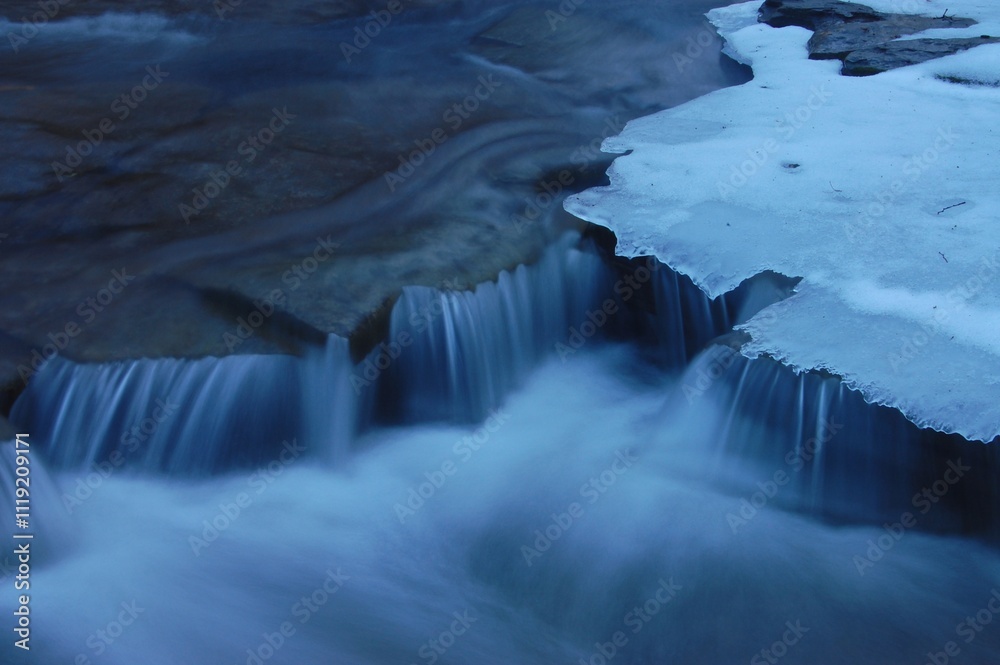 Obraz premium Long exposure of river water with ice, winter concept