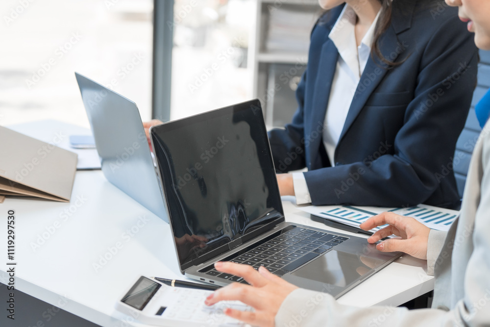 Two Asian businesswomen work on a laptop in an office, pointing at the screen, talking, and smiling with joy as they celebrate positive results of their business success. Two Asian businesswomen work on a laptop in an office, pointing at the screen, talking, and smiling with joy as they celebrate positive results of their business success.