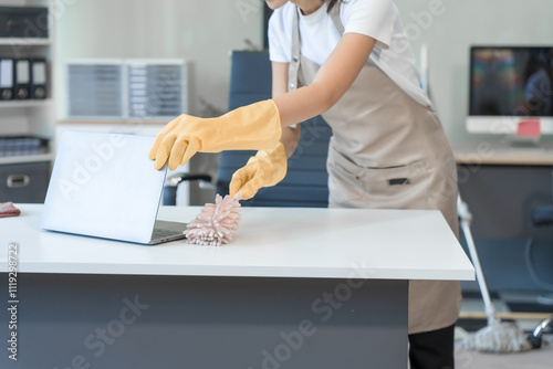 Two Asian housekeepers wear overalls and work together efficiently to clean the living room, study, office.They wipe the windows, mop the floors, inspect the shop to make sure the work is spotless photo