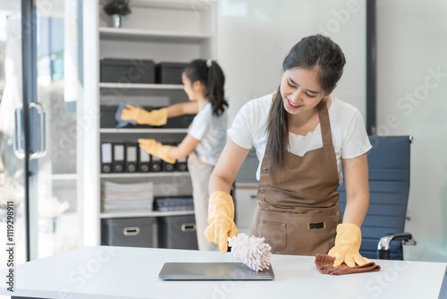 Fotografi Two Asian housekeepers wear overalls and work together efficiently to clean the living room, study, office