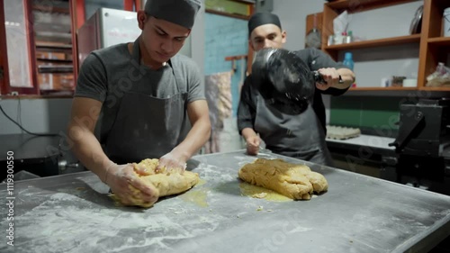 Bakers kneading dough while adding melted butter