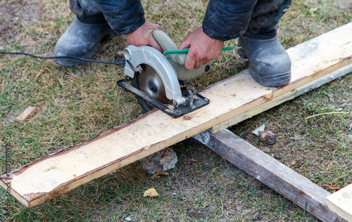 A man is using a power saw to cut a piece of wood