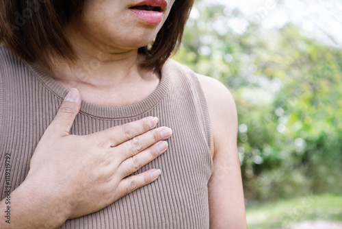 Asian woman suffering heart disease chest pain outdoors, heart attack or panic concept