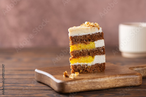 Piece of pumpkin or carrot layered cake with vegan coconut cream, orange confit and walnut with cup of coffee in a wooden board. Sugar, gluten and lactose free. photo