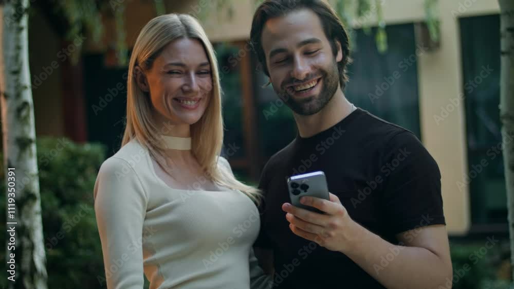 A couple holds a phone, looking at the screen. They can't believe they won a prize so easily in a mobile app. Surprised, they don't show the phone to the camera. They are very happy about winning. A couple holds a phone, looking at the screen. They can't believe they won a prize so easily in a mobile app. Surprised, they don't show the phone to the camera. They are very happy about winning.
