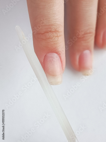 A woman files her nails with a nail file. The manicure process. The shape of the nail. A glass nail file.