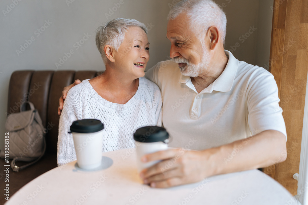 Portrait of beautiful affectionate senior couple enjoying each other company having coffee at cafe, loving looking at each other. Concept of active aging and happy retirement. Portrait of beautiful affectionate senior couple enjoying each other company having coffee at cafe, loving looking at each other. Concept of active aging and happy retirement.