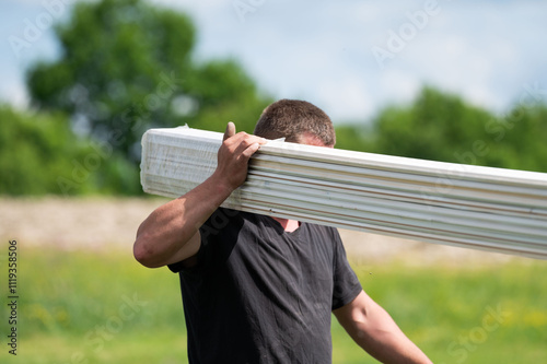 A male worker carries boards for sheathing a gazebo in a lavender field.