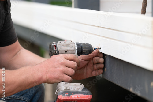 The builder attaches the wall to the gazebo frame using screws and a screwdriver. photo