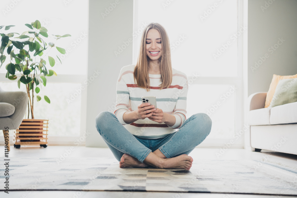Young woman enjoying a relaxing day at home using her phone in the living room