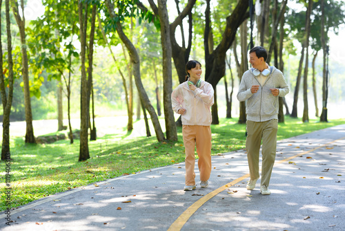 Cheerful middle aged man and his daughter enjoying a light jogging or brisk walking session on park trail