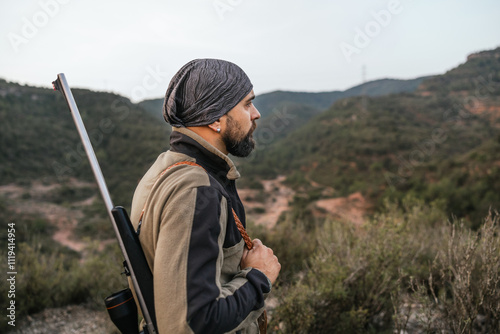 Hunter standing on mountain ridge holding rifle