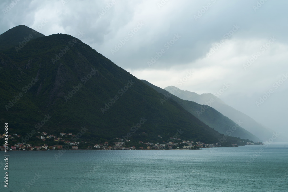 Obraz premium Cloudy mountainside over calm waterscape