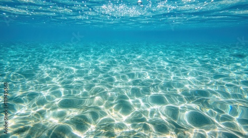 Underwater scene showcasing clear blue water and sunlight reflections on the ocean floor.