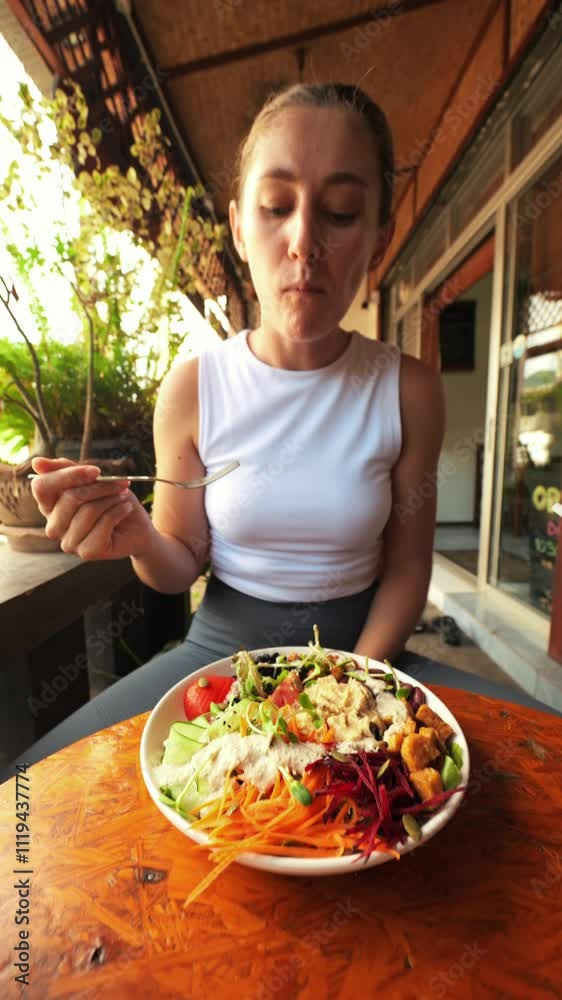 Young Hungry Pleased Woman Eating Buddha Bowl and Drink Kombucha in Restaurant. Smiling Girl Eating Fast Food and Enjoying. Thailand, Pai