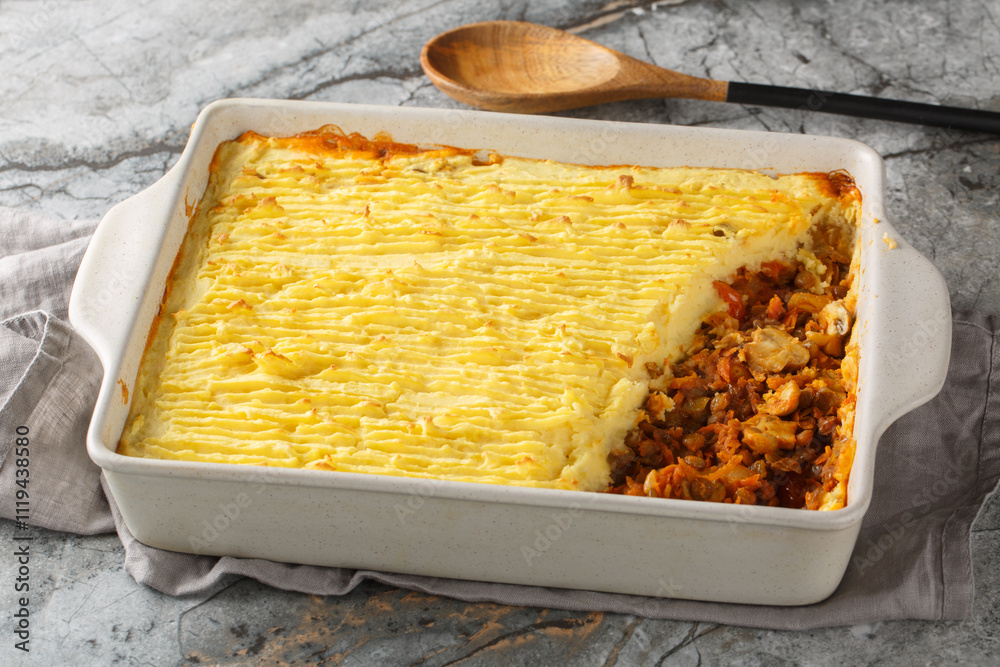 Homemade vegan shepherd's pie with lentils, onions, mushrooms, tomatoes, carrots close-up in a baking dish on the table. Horizontal