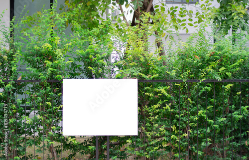 Empty sign, advertising mock-up, banner on fence full of plants for a house