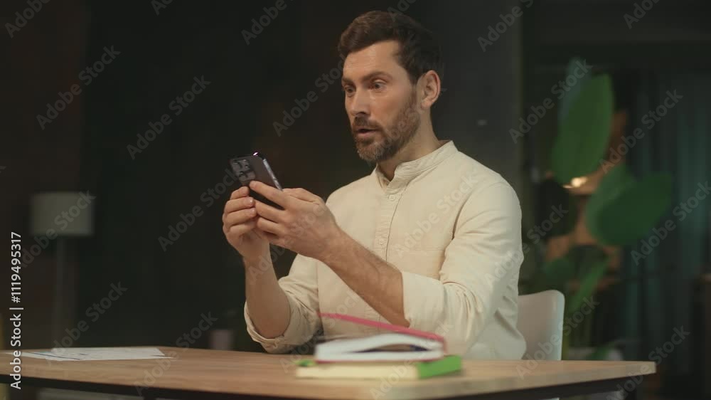 Success bearded man sitting at desk use phone typing chatting in social media smiling feel happy and satisfied. Modern office. Camera moving around. 360 Degree Success bearded man sitting at desk use phone typing chatting in social media smiling feel happy and satisfied. Modern office. Camera moving around. 360 Degree