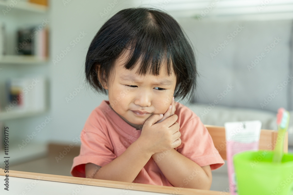 little asian girl presses hand to cheek, suffers from pain in tooth. Teeth decay, dental problems, child emotions and facial expression, oral health care, reducing sweets, fluorine coating. little asian girl presses hand to cheek, suffers from pain in tooth. Teeth decay, dental problems, child emotions and facial expression, oral health care, reducing sweets, fluorine coating.