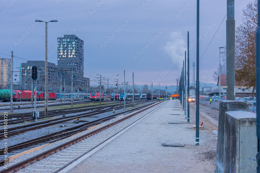 Fototapeta premium New platform on a ljubljana station under construction. Visible new gravel surface, workers, trains and new light posts.