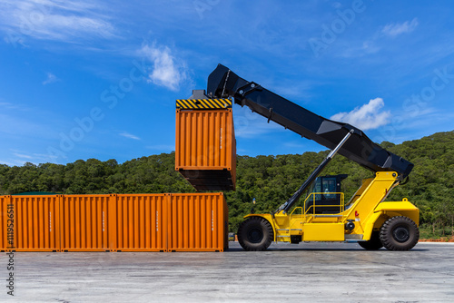 Fotografie Reach stacker cargo forklift container box import export logistic transportation industrial, Reach stacker pick up container, Reach stacker container loader crane lifting maritime cargo container