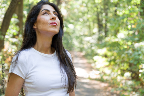 Beautiful woman relaxing and breathing fresh air with sunlight in the summer park