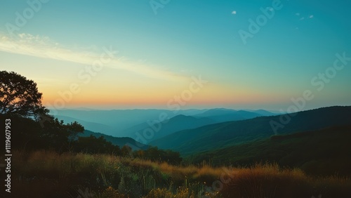 A breathtaking panoramic view of misty mountains at sunrise, showcasing layers of hills and lush greenery bathed in warm golden light
