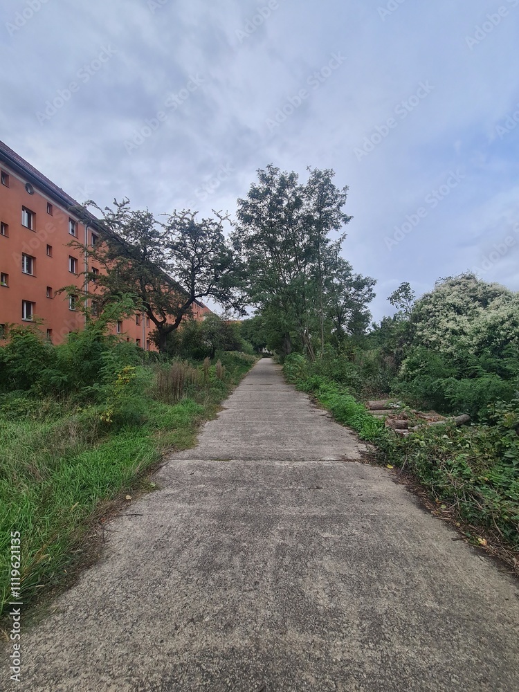 Gehweg durch ein Wohngebiet in Berlin Treptow/Köpenick, mit atmosphärischem Wolkenhimmel Gehweg durch ein Wohngebiet in Berlin Treptow/Köpenick, mit atmosphärischem Wolkenhimmel