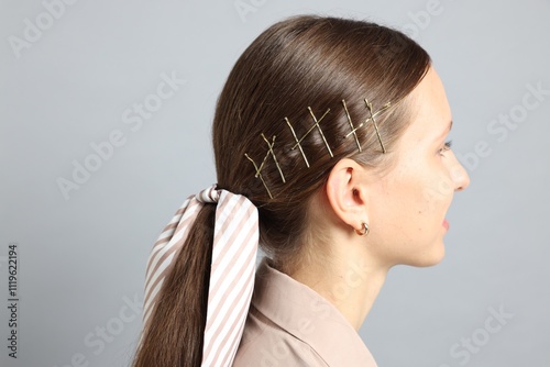 Teenage girl with stylish hair clips and bandana on light grey background photo