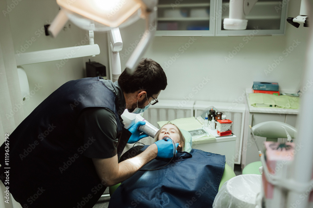 Cropped portrait of little girl with pigtails hair sitting in dental chair looking at camera. A doctor in gloves holds examination tools. Children's dentistry. Part of a series Cropped portrait of little girl with pigtails hair sitting in dental chair looking at camera. A doctor in gloves holds examination tools. Children's dentistry. Part of a series