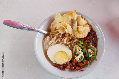 Bubur Ayam, a traditional Indonesian food consisting of white rice porridge, shredded chicken, cakwe, fried soybeans, crackers, green onions and eggs. photo