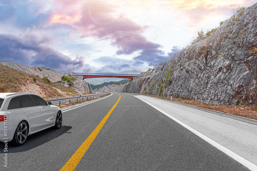 White car driving on highway with mountains in background. Car travel - concept.
