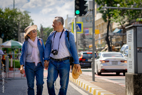 Asian retired couple happily hang out together in city full buildings in capital Thailand Bangkok