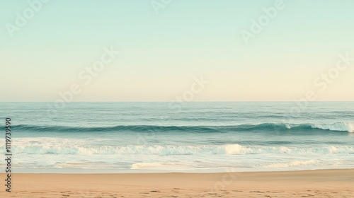 A tranquil beach scene with soft, foamy waves breaking on the shore under a clear blue sky.