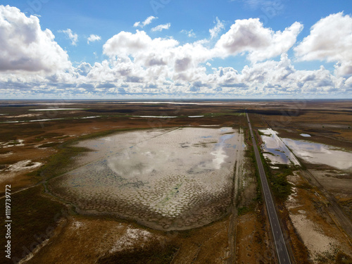 An aerial view showcasing a swamp with a winding road crossing through it