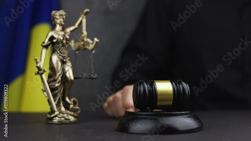 Judge with gavel and Themis Lady Justice against flag of Ukraine and dark background.