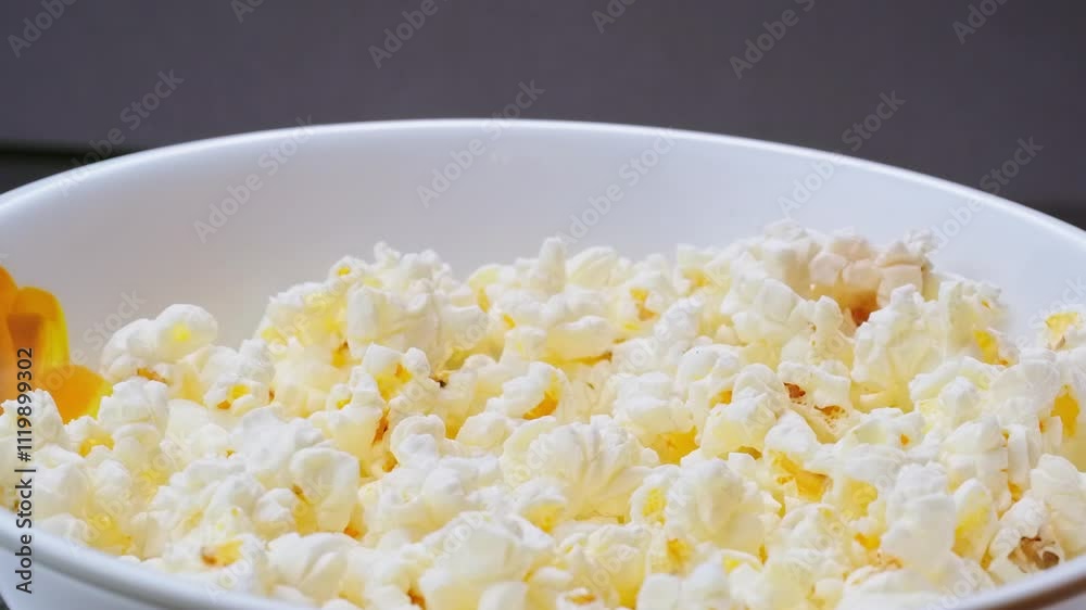 Man's hand taking popcorn from rotating bowl, leisure time snack while watching a movie. 