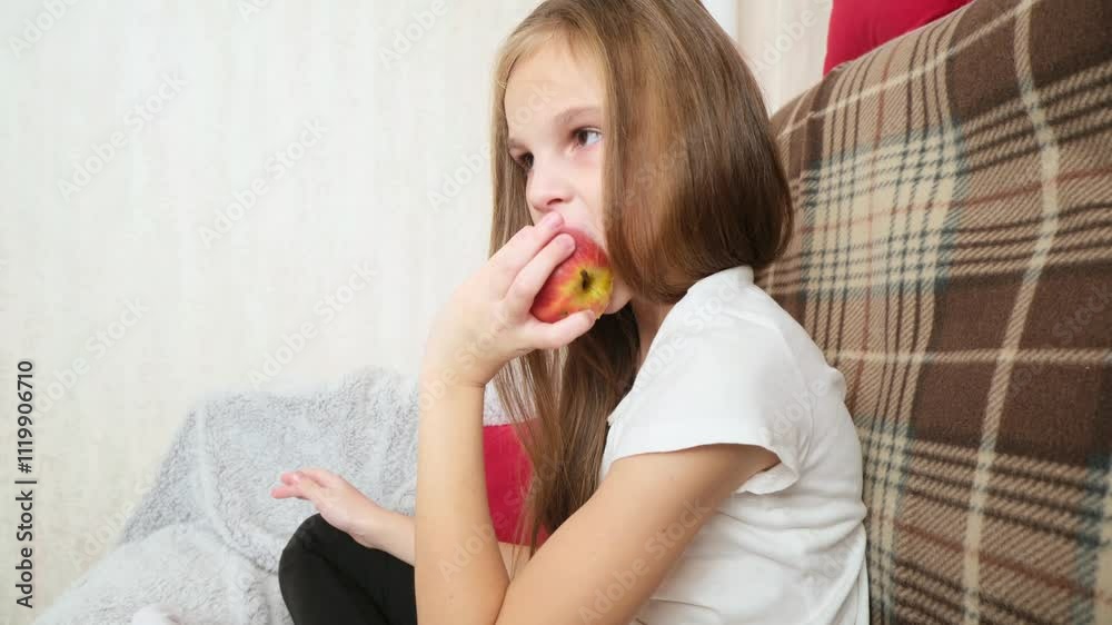Happy little girl eating apple sitting on the sofa living-room Happy little girl eating apple sitting on the sofa living-room