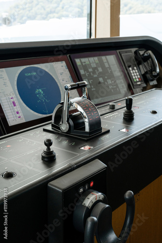 Detail shot of the throttle controls, radar and ship's systems in the bridge of a modern superyacht, with dark leather interior