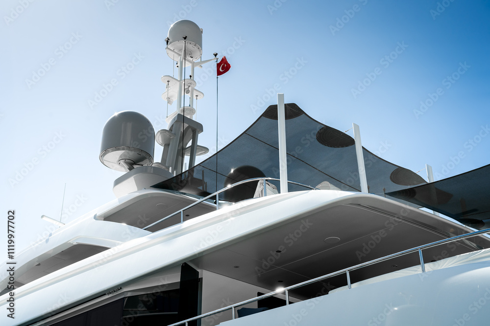 Naklejka premium Detail of stern and antennas of a spotless modern superyacht at dock in Gocek marina in Turkey, with blue sky